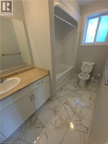 White vanity with built-in sink, tan countertop, and extensive wall mirror - 998 Mapleridge Street, London, ON - Indoor Photo Showing Bathroom