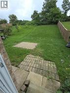 Expansive green space with mature trees, fenced perimeter, and paver stone patio areas - 