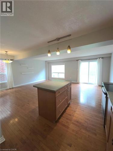 Hardwood flooring throughout, kitchen island with built-in storage, sliding glass door, white framed windows, and pendant lighting - 998 Mapleridge Street, London, ON - Indoor Photo Showing Other Room