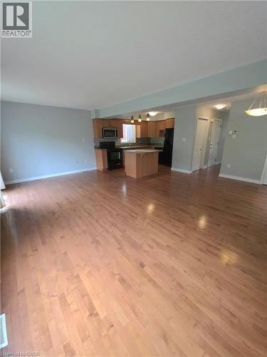 Hardwood flooring extending throughout, kitchen with wood-finish cabinetry, stainless steel microwave, and tile backsplash - 998 Mapleridge Street, London, ON - Indoor
