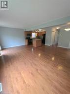 Hardwood flooring extending throughout, kitchen with wood-finish cabinetry, stainless steel microwave, and tile backsplash - 