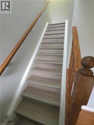 Staircase with wood-finish treads and risers, complemented by a natural wood handrail and newel post - 998 Mapleridge Street, London, ON - Indoor Photo Showing Other Room