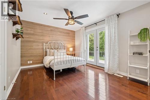 Hardwood flooring, wood-finish accent wall, French doors, ceiling fan with integrated lighting, and recessed lighting - 267 Abraham Street, Cambridge, ON - Indoor Photo Showing Bedroom