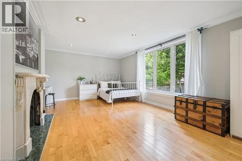 Hardwood flooring, recessed lighting, ornate fireplace with a green tile hearth, crown molding, and large window - 267 Abraham Street, Cambridge, ON - Indoor Photo Showing Bedroom