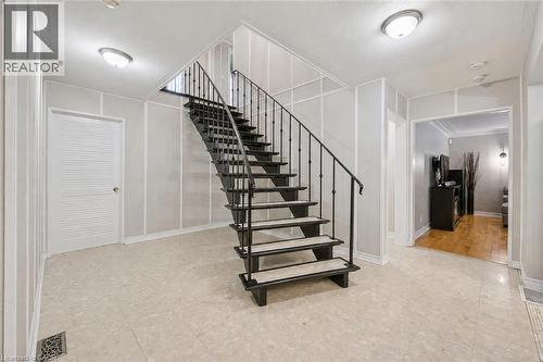 Foyer featuring tile flooring, a curved staircase with wrought iron railing, and paneling accents - 267 Abraham Street, Cambridge, ON - Indoor Photo Showing Other Room