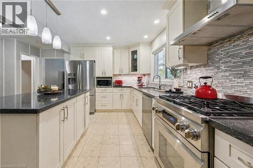 Spacious kitchen featuring an island with pendant lighting, stone countertops, stainless steel appliances, white cabinetry, and a tile backsplash - 267 Abraham Street, Cambridge, ON - Indoor Photo Showing Kitchen With Upgraded Kitchen