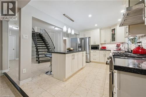 Kitchen featuring light-toned cabinetry, dark countertops, a tile backsplash, and stainless steel appliances - 267 Abraham Street, Cambridge, ON - Indoor Photo Showing Kitchen With Upgraded Kitchen