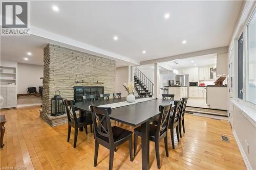 Hardwood flooring, stone fireplace, recessed lighting, white built-in shelving, and a prominent staircase with metal railings - 267 Abraham Street, Cambridge, ON - Indoor Photo Showing Dining Room