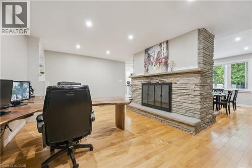 Central stone fireplace feature, wood-finish flooring, recessed lighting, built-in shelving, and large windows - 267 Abraham Street, Cambridge, ON - Indoor Photo Showing Office