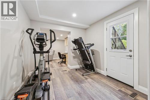 Wood-finish flooring throughout, recessed lighting, and a white paneled door with a glass insert - 267 Abraham Street, Cambridge, ON - Indoor Photo Showing Gym Room