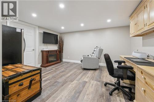 Wood-finish flooring, recessed lighting, built-in desk, built-in cabinetry, and a wall-mounted television - 267 Abraham Street, Cambridge, ON - Indoor Photo Showing Office