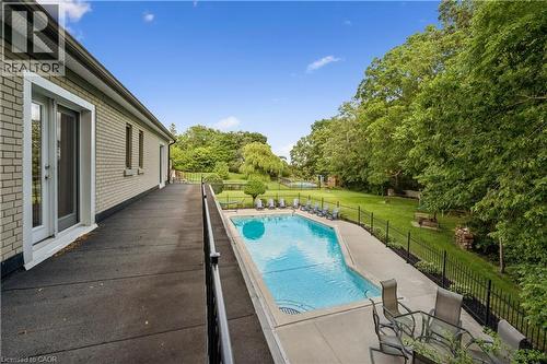 Brick exterior with sliding glass doors, concrete patio, inground swimming pool, and a surrounding wrought iron fence - 267 Abraham Street, Cambridge, ON - Outdoor With In Ground Pool
