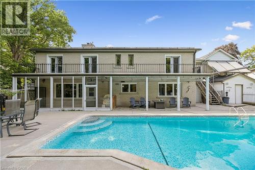 Brick exterior with upper-level balcony featuring wrought iron railing, screened-in porch, covered patio area, and in-ground swimming pool with integrated steps - 267 Abraham Street, Cambridge, ON - Outdoor With In Ground Pool