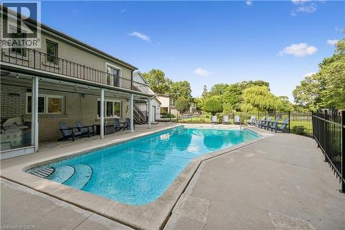 Exterior brick façade, covered patio, second-story balcony with metal railing, in-ground swimming pool with integrated steps, and concrete pool deck - 267 Abraham Street, Cambridge, ON - Outdoor With In Ground Pool