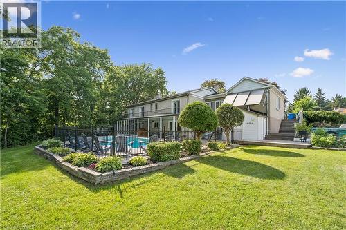 Expansive backyard featuring an in-ground pool, black perimeter fencing, a wooden deck, and mature landscaping - 267 Abraham Street, Cambridge, ON - Outdoor
