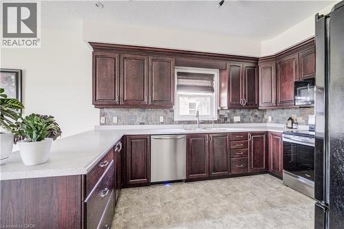 Kitchen featuring wood-finish cabinetry, light-toned countertops, and a tiled backsplash - 64 Kropf Drive, Baden, ON - Indoor Photo Showing Kitchen