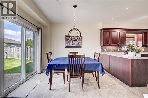 Sliding glass patio door, Linoleum flooring, dark wood cabinetry, light countertops, and a circular pendant light fixture - 64 Kropf Drive, Baden, ON - Indoor Photo Showing Dining Room