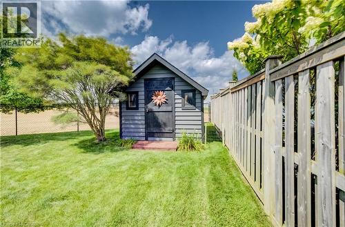 Grassed yard featuring a wood storage shed with shiplap siding, wood privacy fencing, and mature trees - 64 Kropf Drive, Baden, ON - Outdoor