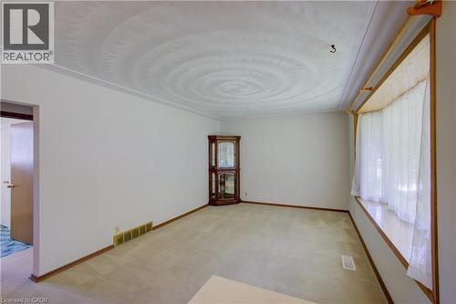 Carpeted room featuring a bay window with wood trim, wood baseboards, and a patterned ceiling - 52 Queenston Crescent, Kitchener, ON - Indoor Photo Showing Other Room
