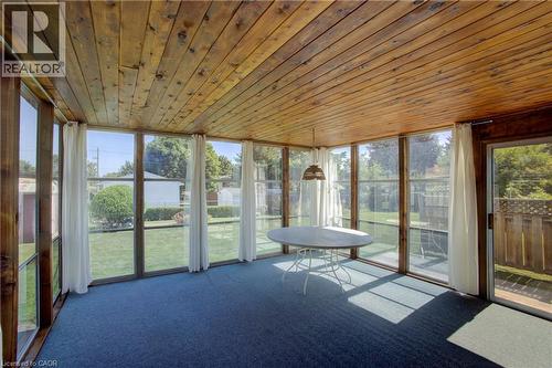 Wood-paneled ceiling, wall-to-wall windows, blue carpeting, sliding glass door, and a hanging light fixture - 52 Queenston Crescent, Kitchener, ON - Outdoor With Exterior