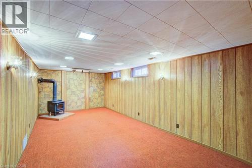 Wood paneling, a wood-burning stove, orange carpeting, and integrated wall sconces - 52 Queenston Crescent, Kitchener, ON - Indoor Photo Showing Living Room With Fireplace