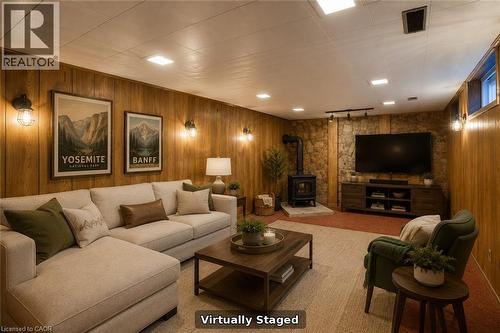 Wood-paneled walls featuring sconce lighting, stone accent wall, recessed lighting, and a wood-burning stove - 52 Queenston Crescent, Kitchener, ON - Indoor Photo Showing Other Room