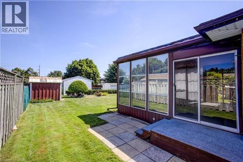 Expansive grassy yard featuring a stone patio, enclosed sunroom with sliding glass door, and a detached storage shed - 52 Queenston Crescent, Kitchener, ON - Outdoor