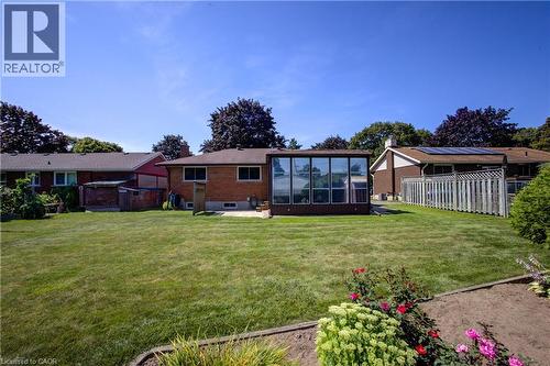 Expansive lawn area, brick exterior with a sunroom addition, rear patio, and garden beds - 52 Queenston Crescent, Kitchener, ON - Outdoor