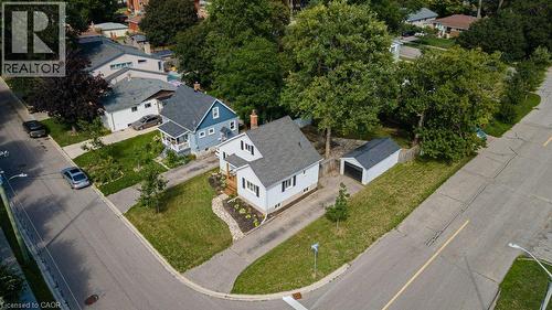 White exterior with dark shutters, paved driveway, landscaped front yard, detached garage, and mature trees - 99 Shantz Lane, Kitchener, ON - Outdoor With View