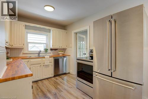White cabinetry, wood-finish countertops, stainless steel appliances, wood-finish flooring, and a single-basin sink - 99 Shantz Lane, Kitchener, ON - Indoor Photo Showing Kitchen With Double Sink