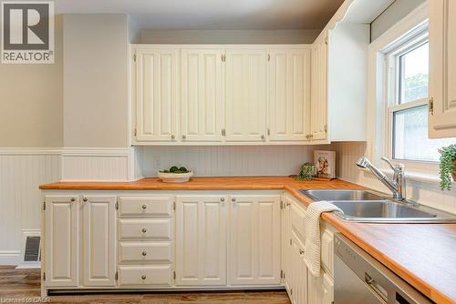 White cabinetry, wood-finish countertops, stainless steel double-basin sink, and a built-in dishwasher - 99 Shantz Lane, Kitchener, ON - Indoor Photo Showing Kitchen With Double Sink