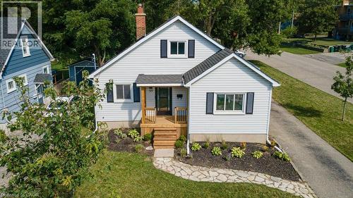 Gable roofline, light-colored siding, dark shutters, covered front porch with wood decking, and a stone walkway - 99 Shantz Lane, Kitchener, ON - Outdoor