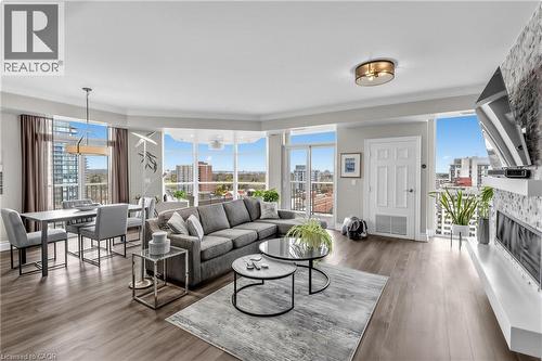 Open-concept living space with wood-finish flooring, floor-to-ceiling windows, and a built-in electric fireplace - 1477 Lakeshore Road Unit# Ph 1, Burlington, ON 