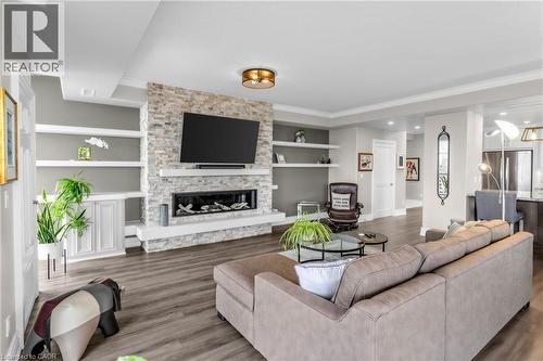 Wood-finish flooring, stone-clad fireplace with a linear insert, built-in shelving, and recessed lighting - 1477 Lakeshore Road Unit# Ph 1, Burlington, ON 