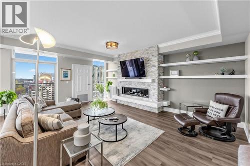 Wood-finish flooring throughout, complemented by a stone-faced fireplace with an integrated linear firebox - 1477 Lakeshore Road Unit# Ph 1, Burlington, ON 