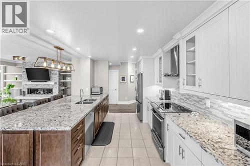 Spacious kitchen featuring an extended island with dual sinks, white shaker cabinetry, stainless steel appliances, and a mosaic tile backsplash - 1477 Lakeshore Road Unit# Ph 1, Burlington, ON 