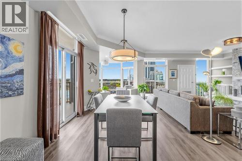 Open-concept living area featuring wood-finish flooring, a contemporary dining pendant, and a sliding glass door to a balcony - 1477 Lakeshore Road Unit# Ph 1, Burlington, ON 