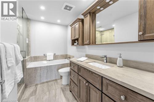 Bathroom featuring a soaking tub, glass-enclosed shower, wood-finish vanity with an integrated sink, and recessed lighting - 1477 Lakeshore Road Unit# Ph 1, Burlington, ON 