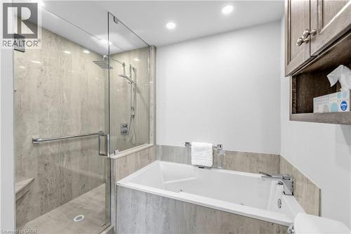 Spacious bathroom featuring a built-in soaking tub, glass-enclosed shower with a rainfall showerhead, and a corner shower bench - 1477 Lakeshore Road Unit# Ph 1, Burlington, ON 