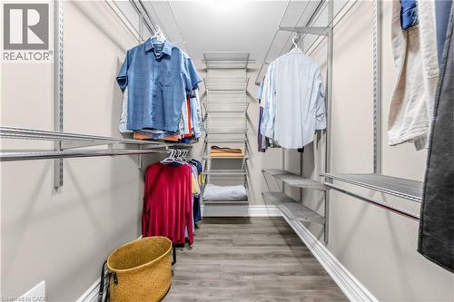 Walk-in closet featuring floor-to-ceiling adjustable shelving, multiple hanging rods, durable wood-finish flooring, and light-toned wall paint - 1477 Lakeshore Road Unit# Ph 1, Burlington, ON 