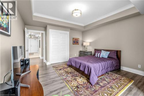 Recessed tray ceiling, wood-finish flooring, paneled bifold closet doors, and a decorative semi-flush mount light fixture - 1477 Lakeshore Road Unit# Ph 1, Burlington, ON 