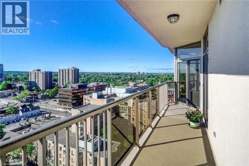 Private balcony with a concrete surface, glass and metal railing, and a wall-mounted exterior light fixture - 1477 Lakeshore Road Unit# Ph 1, Burlington, ON 