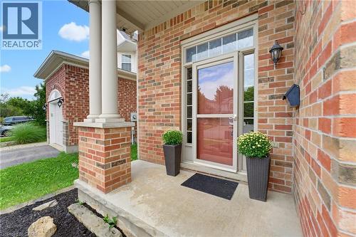 Brick exterior with a covered concrete porch, decorative columns, and an integrated overhead transom window - 592 Little Dover Crescent, Waterloo, ON - Outdoor