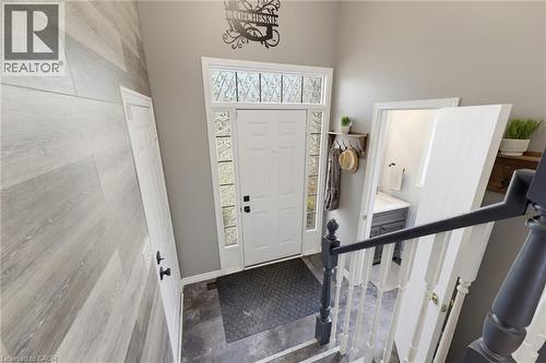 Entryway featuring a white door with decorative glass sidelights and transom window, wood-finish flooring, and a staircase with painted newel posts and railings - 592 Little Dover Crescent, Waterloo, ON - Indoor Photo Showing Other Room