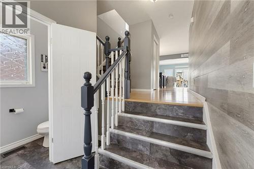 Staircase with dark-toned treads and balusters, light wood-finish flooring on the landing, and a paneled accent wall - 592 Little Dover Crescent, Waterloo, ON - Indoor Photo Showing Other Room