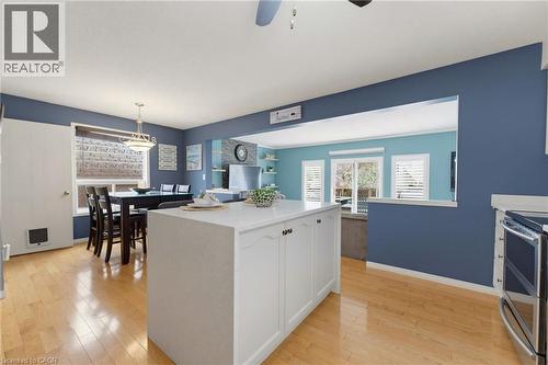 Kitchen island with white cabinetry and countertop, wood-finish flooring, and stainless steel range - 592 Little Dover Crescent, Waterloo, ON - Indoor Photo Showing Other Room