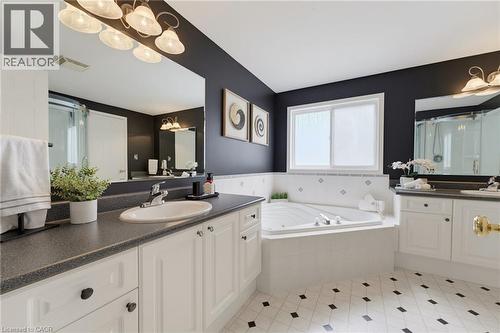 Dual vanity with integrated sinks, built-in corner soaking tub, white cabinetry, large vanity mirrors, and patterned floor tile - 592 Little Dover Crescent, Waterloo, ON - Indoor Photo Showing Bathroom