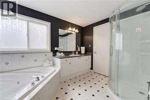 White soaking tub with chrome fixtures, complete with a tiled surround - 592 Little Dover Crescent, Waterloo, ON - Indoor Photo Showing Bathroom