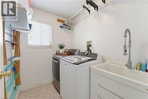 White utility sink with a chrome pull-down faucet, accompanied by a window with blinds and light-toned tile flooring - 592 Little Dover Crescent, Waterloo, ON - Indoor Photo Showing Laundry Room