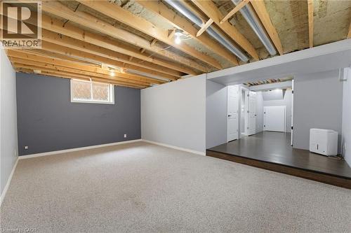 Unfinished ceiling with exposed joists, carpeted flooring, window, and a raised platform with wood-finish flooring - 592 Little Dover Crescent, Waterloo, ON - Indoor Photo Showing Basement